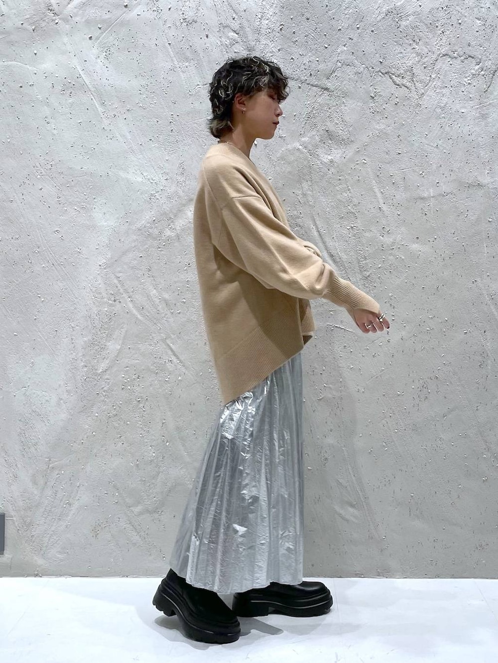 ブラック系のブーツ、ベージュ系のニット/セーター、シルバー系のスカートを着用したレディースの秋コーディネートの2枚目の写真