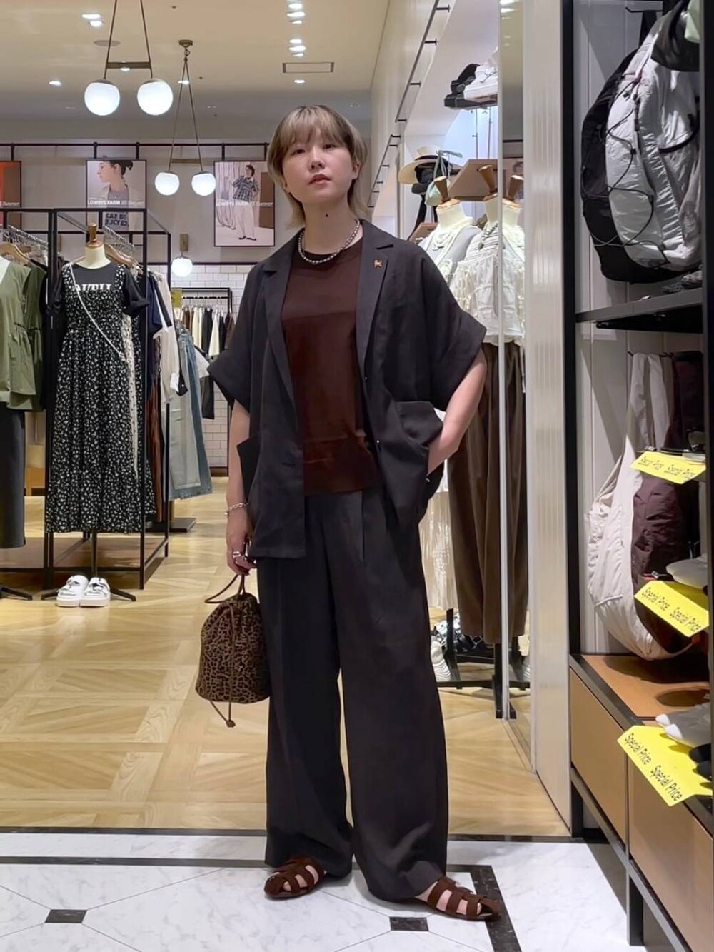 グレー系のテーラードジャケット、グレー系のスラックス、ブラウン系のサンダルを着用したレディースの夏コーディネートの5枚目の写真