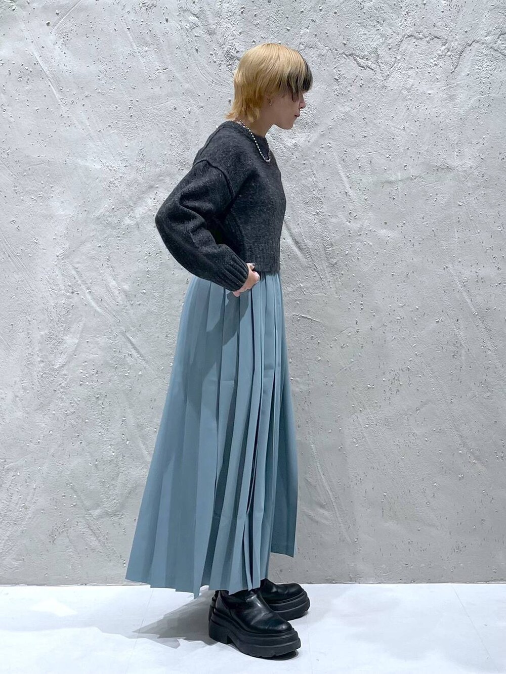 グレー系のニット/セーター、ブルー系のスカートを着用したレディースの秋コーディネートの4枚目の写真