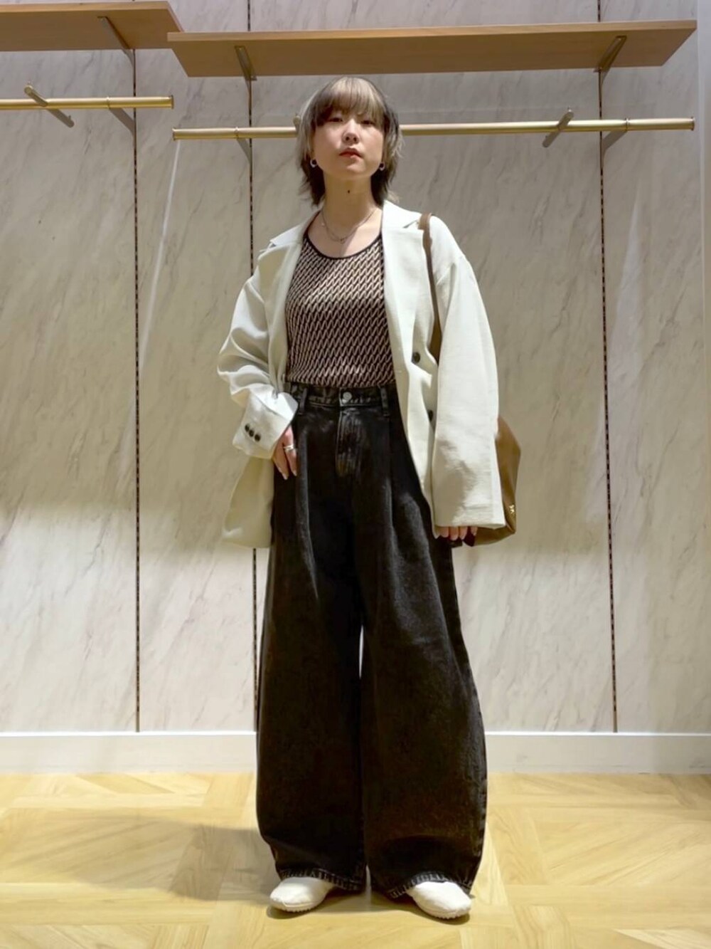 ブラウン系のショルダーバッグ、ホワイト系のテーラードジャケット、ブラック系のデニムパンツを着用したレディースの春コーディネートの4枚目の写真