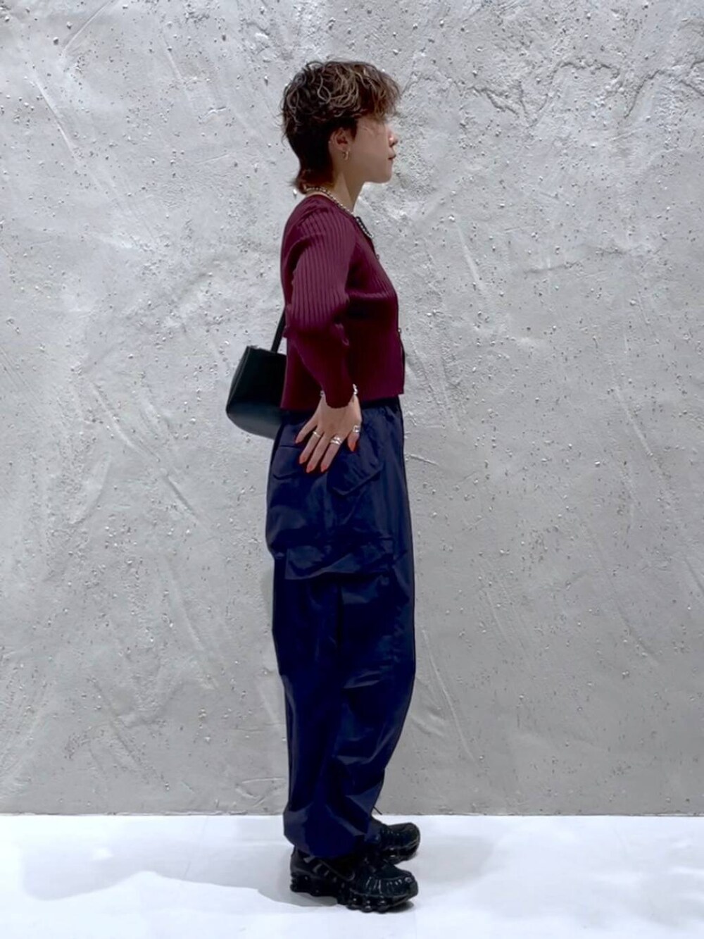 レッド系のカーディガン/ボレロ、ブルー系のカーゴパンツ、ブラック系のショルダーバッグを着用したレディースの秋コーディネートの4枚目の写真
