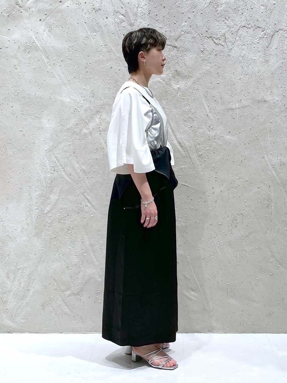シルバー系のサンダル、ホワイト系のTシャツ/カットソー、ブラック系のワンピースを着用したレディースの春コーディネートの2枚目の写真