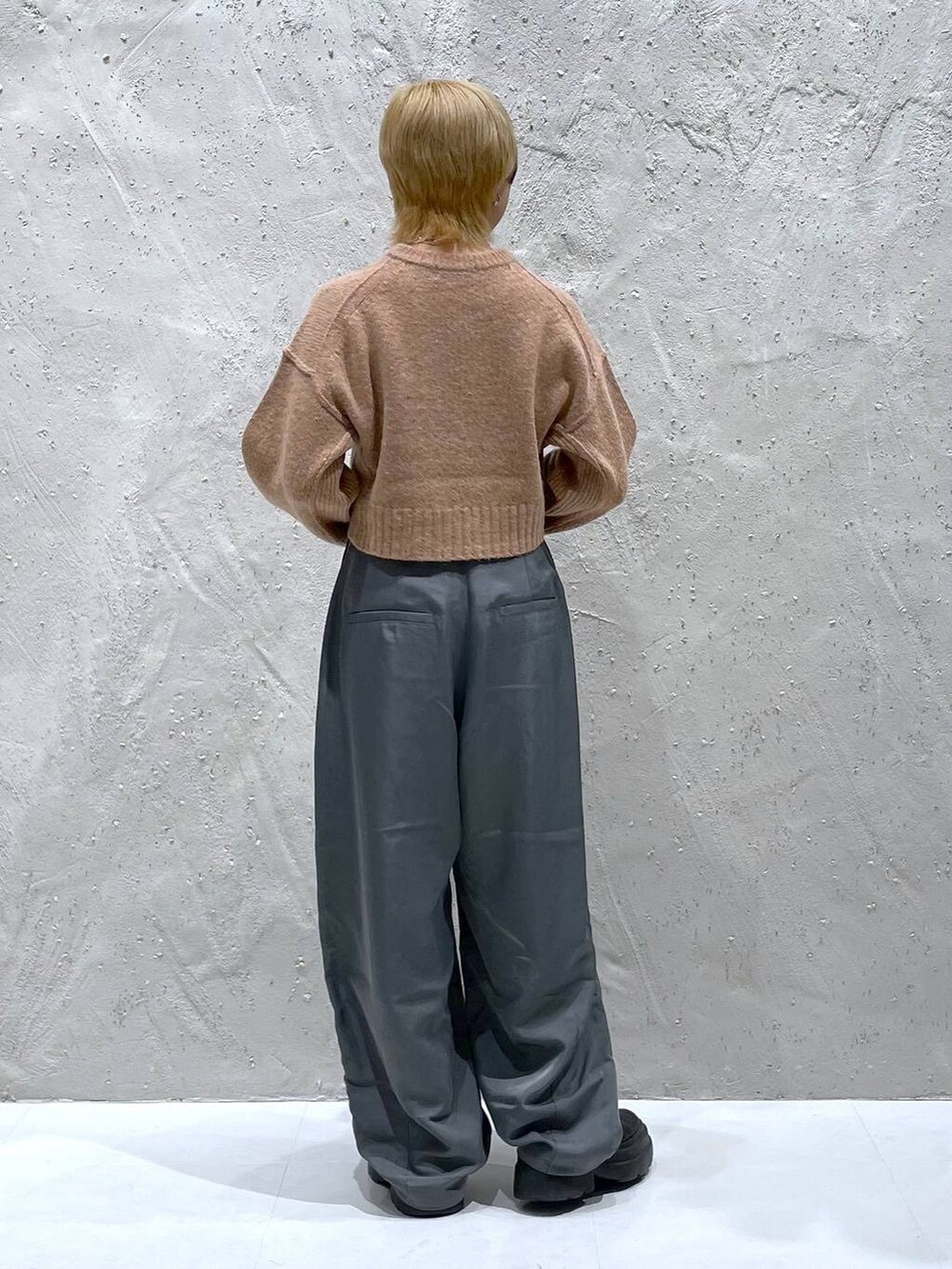 オレンジ系のニット/セーター、グレー系のその他パンツを着用したレディースの秋コーディネートの3枚目の写真