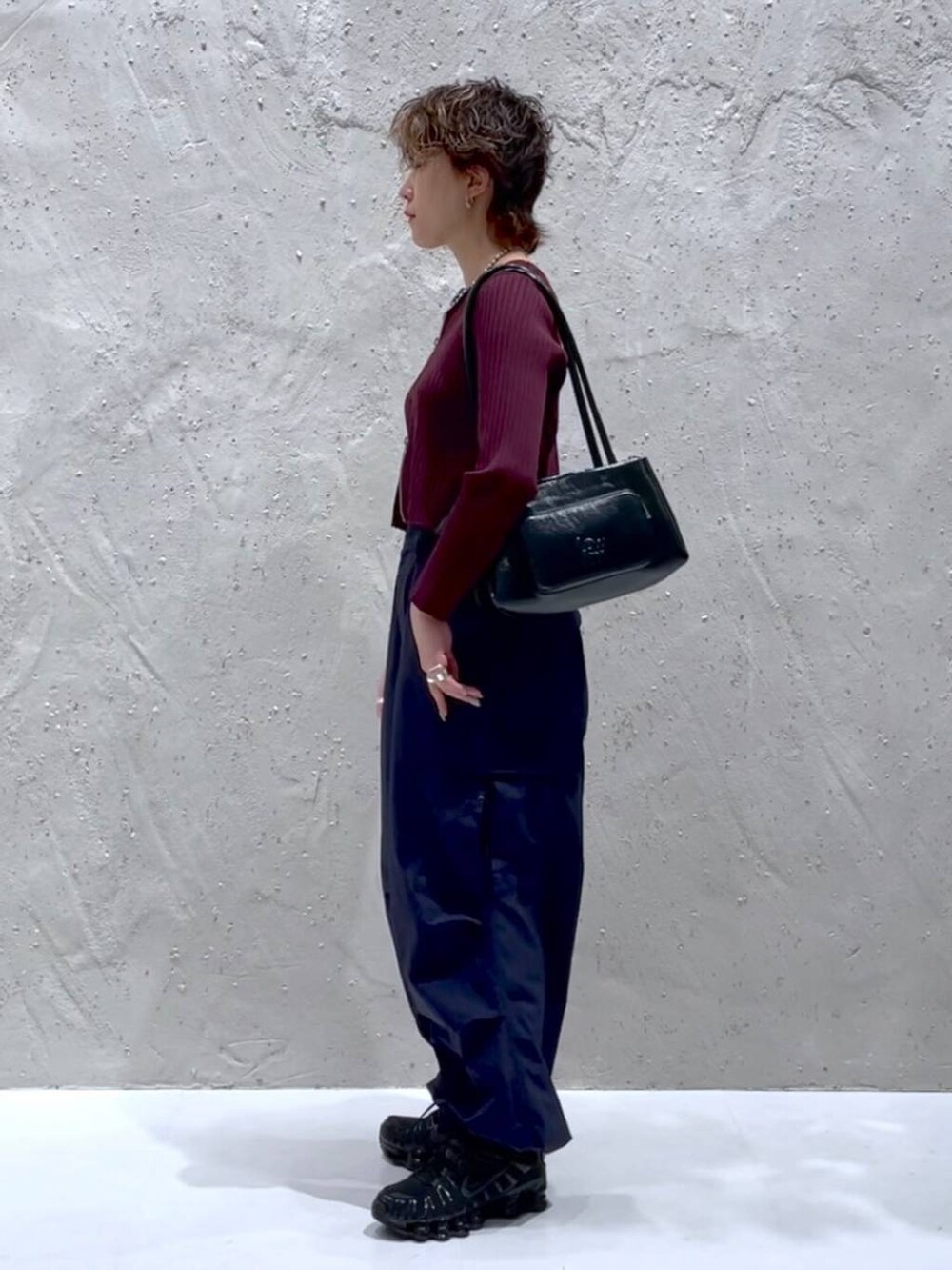 レッド系のカーディガン/ボレロ、ブルー系のカーゴパンツ、ブラック系のショルダーバッグを着用したレディースの秋コーディネートの2枚目の写真