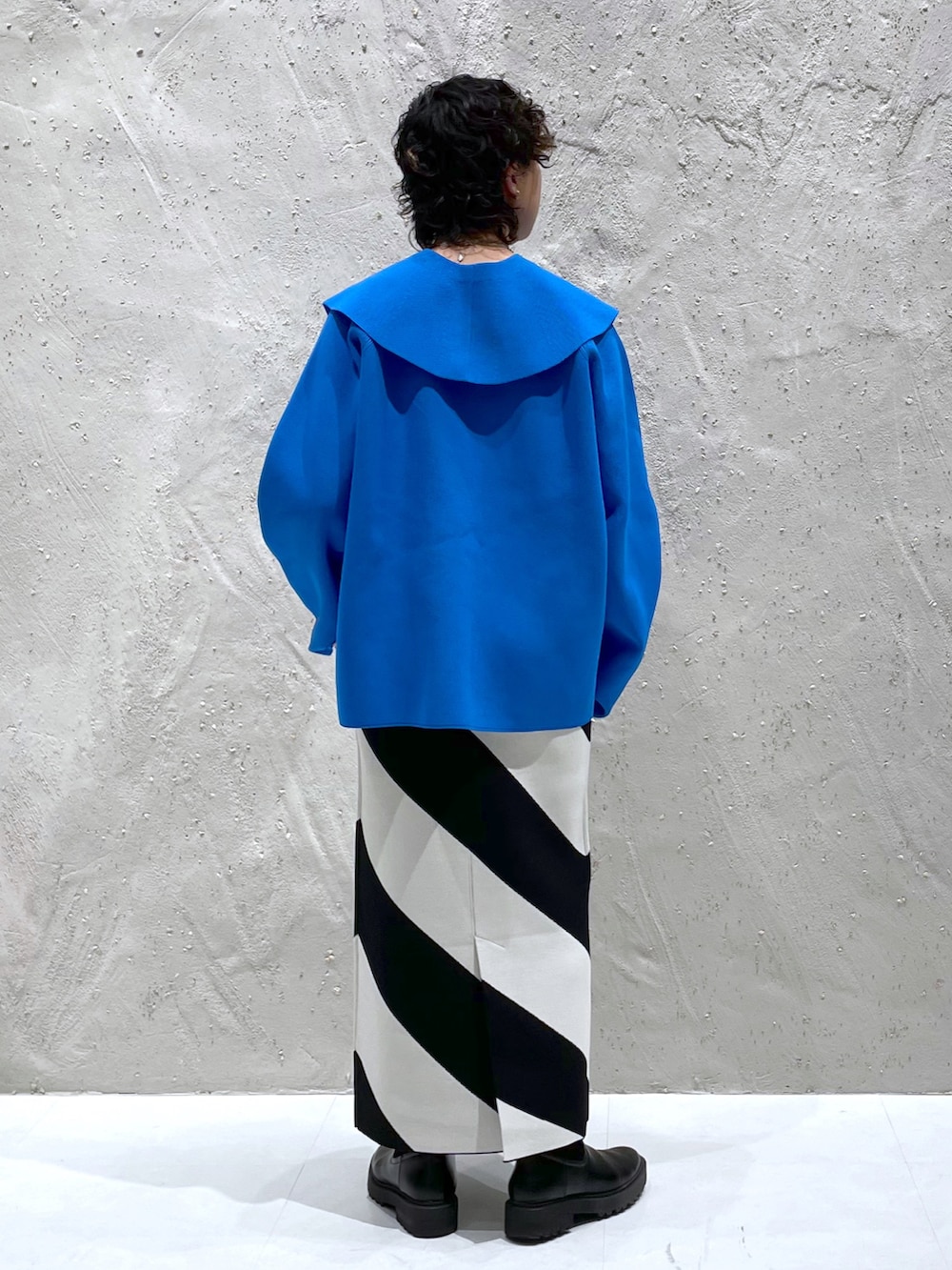 ブルー系のニット/セーター、ブラック系のスカート、ブラック系のブーツを着用したレディースの冬コーディネートの3枚目の写真