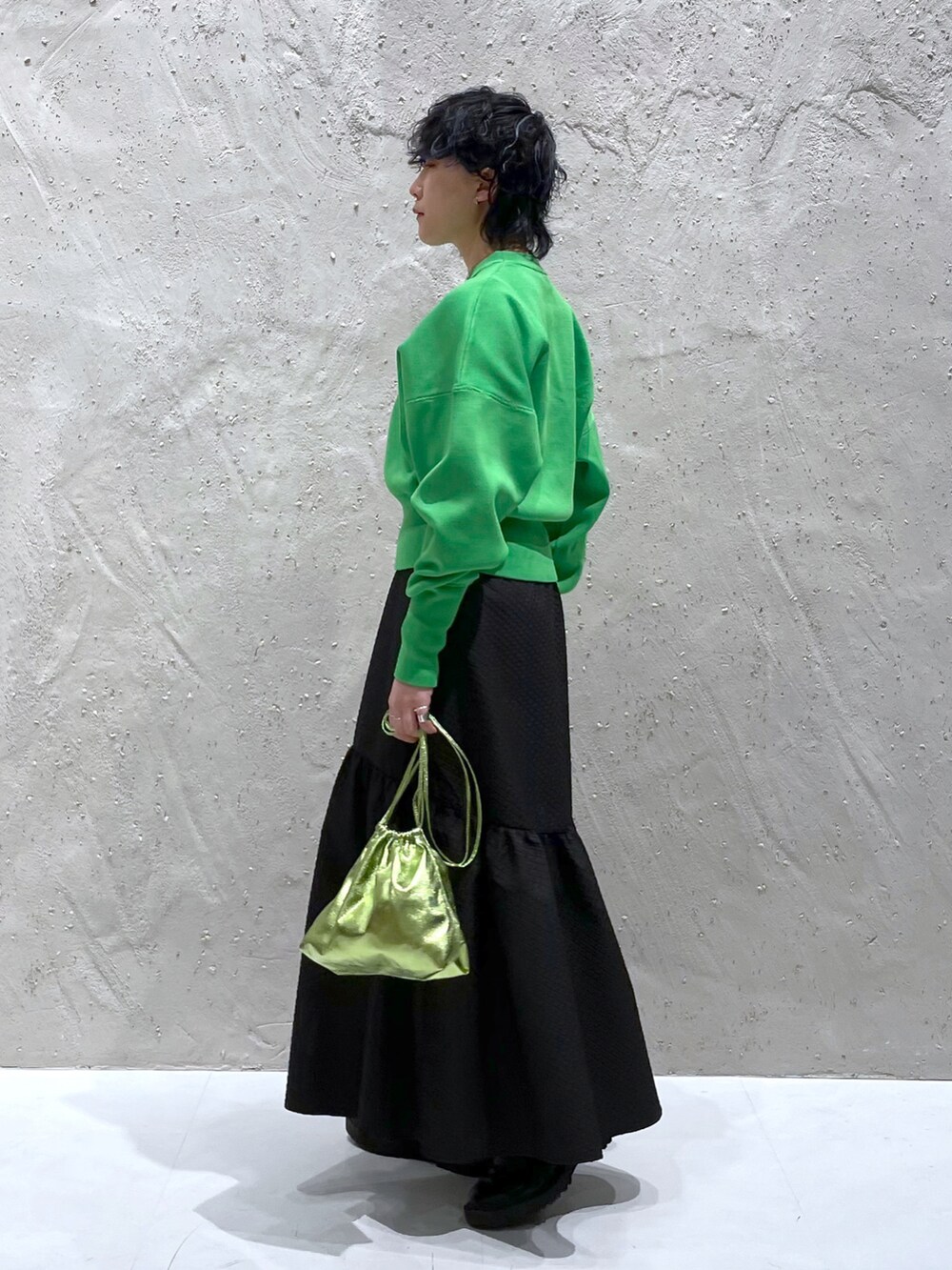 グリーン系のスウェット、ブラック系のスカート、グリーン系のショルダーバッグを着用したレディースの春コーディネートの2枚目の写真