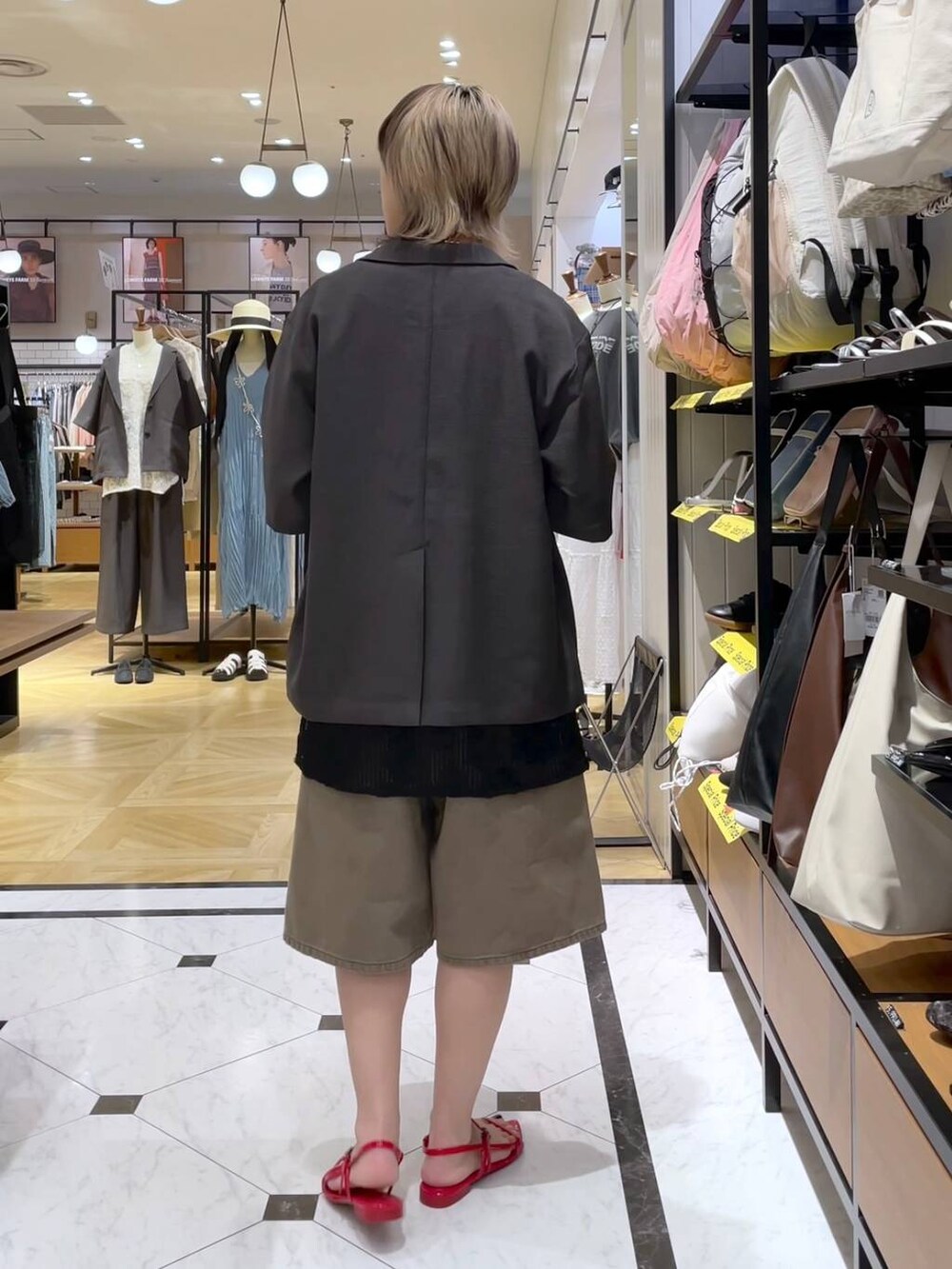 グレー系のテーラードジャケット、レッド系のサンダル、ブラウン系のデニムパンツを着用したレディースの春コーディネートの3枚目の写真