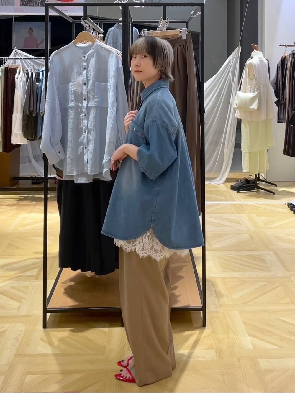 レッド系のサンダル、ブルー系のシャツ/ブラウス、ベージュ系のスラックスを着用したレディースの春コーディネートの2枚目の写真