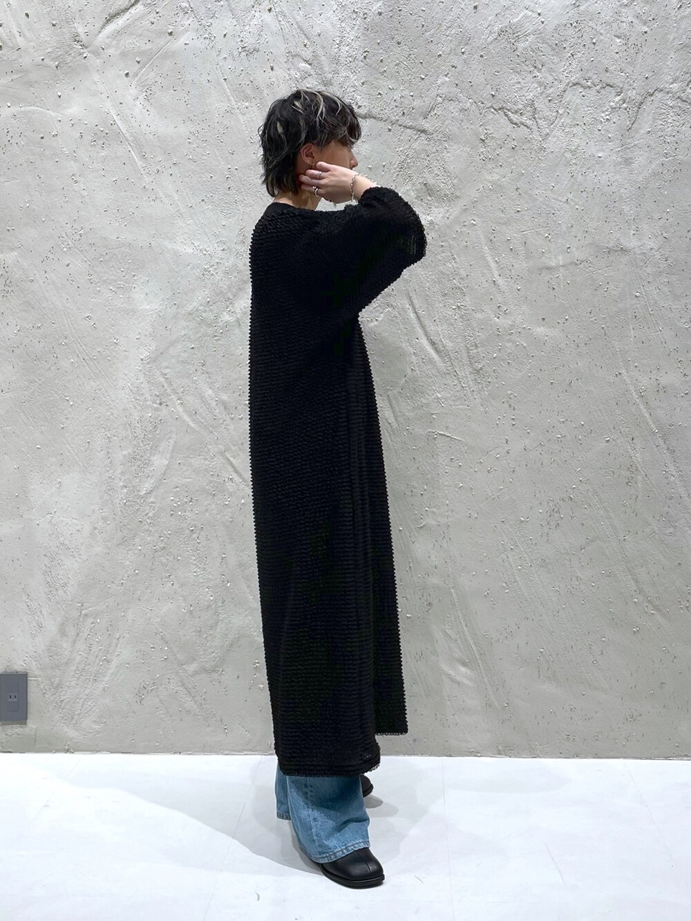 ブラック系のワンピース、ブルー系のデニムパンツ、ブラック系のサンダルを着用したレディースの春コーディネートの2枚目の写真