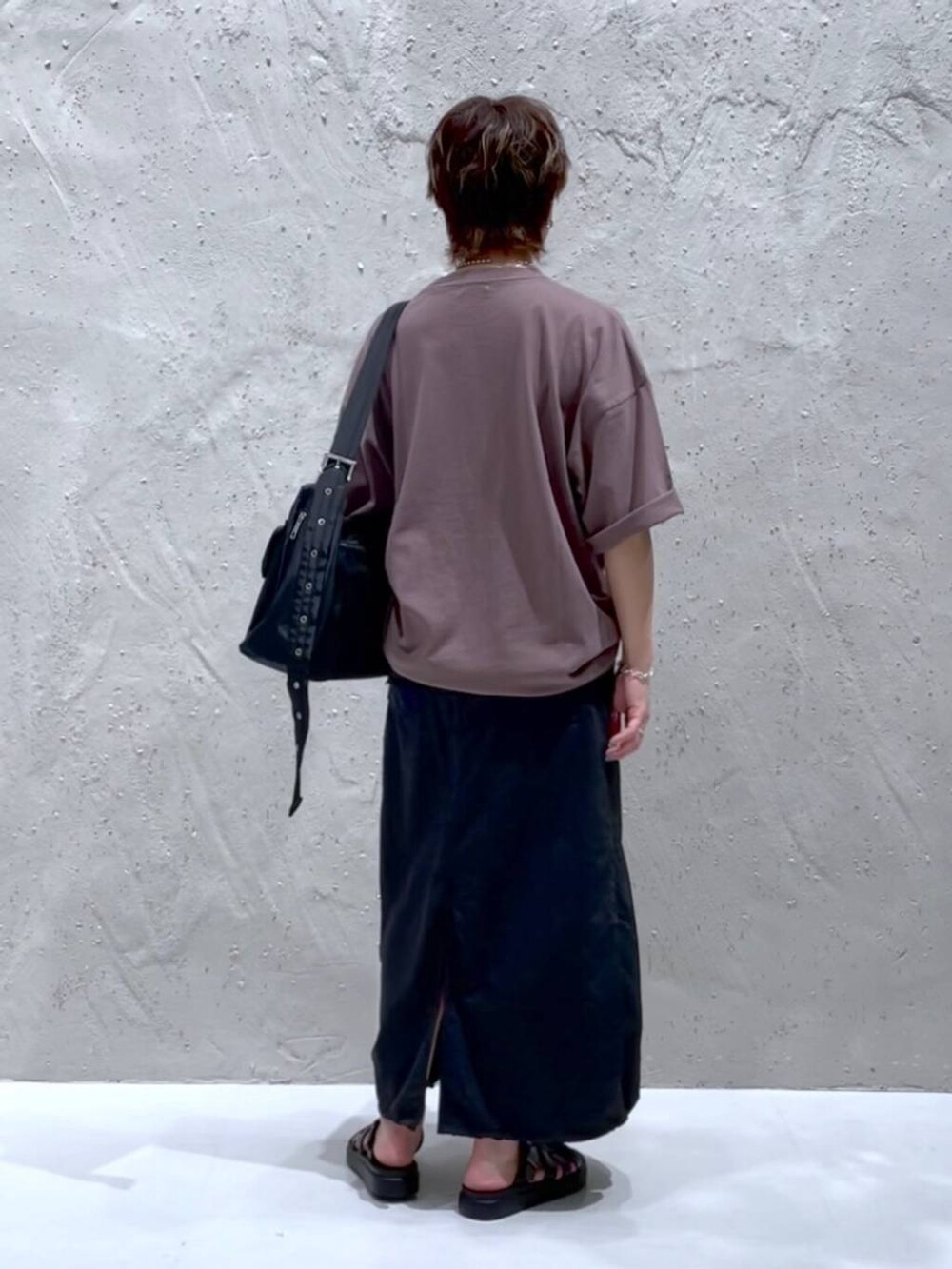 ブラック系のデニムスカート、ブラック系のショルダーバッグ、ブラック系のスニーカーを着用したレディースの夏コーディネートの3枚目の写真