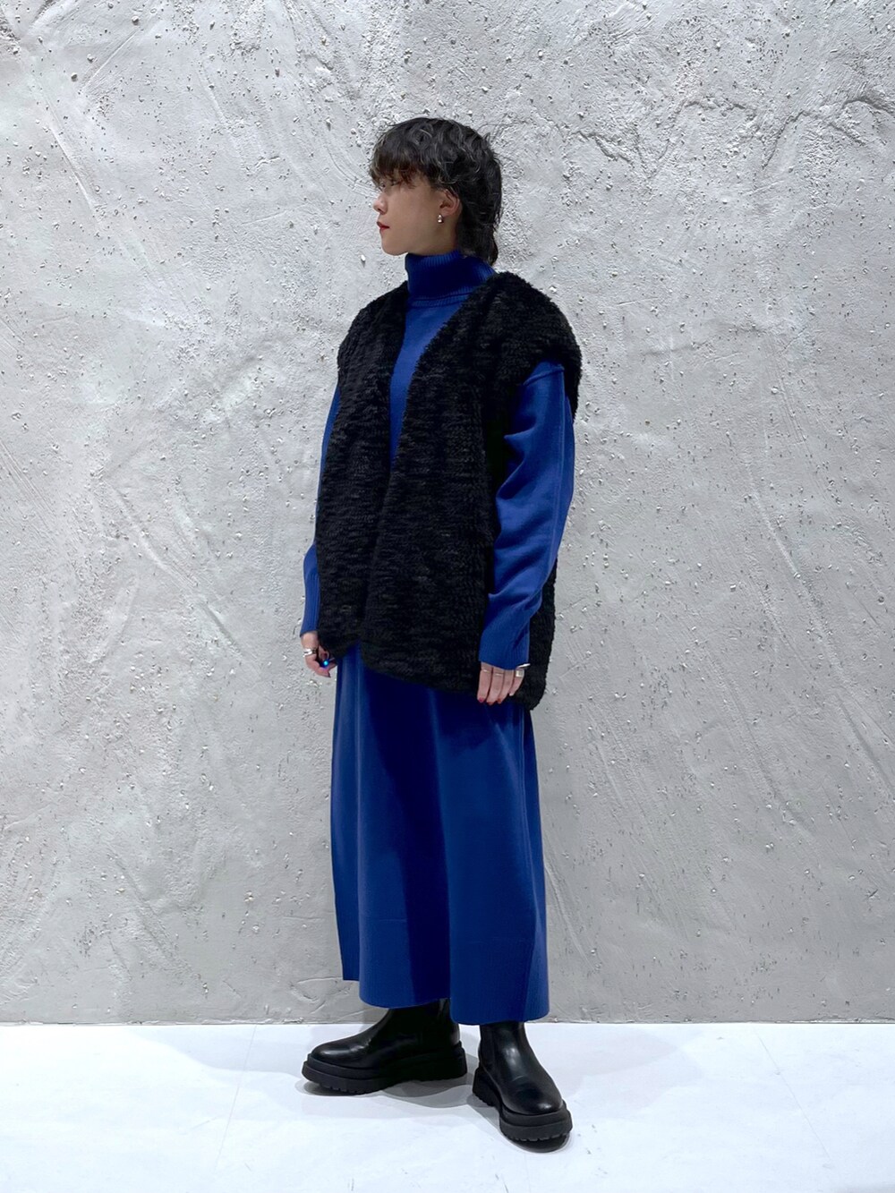 ブラック系のブルゾン、ブルー系のワンピース、ブラック系のブーツを着用したレディースの冬コーディネートの3枚目の写真