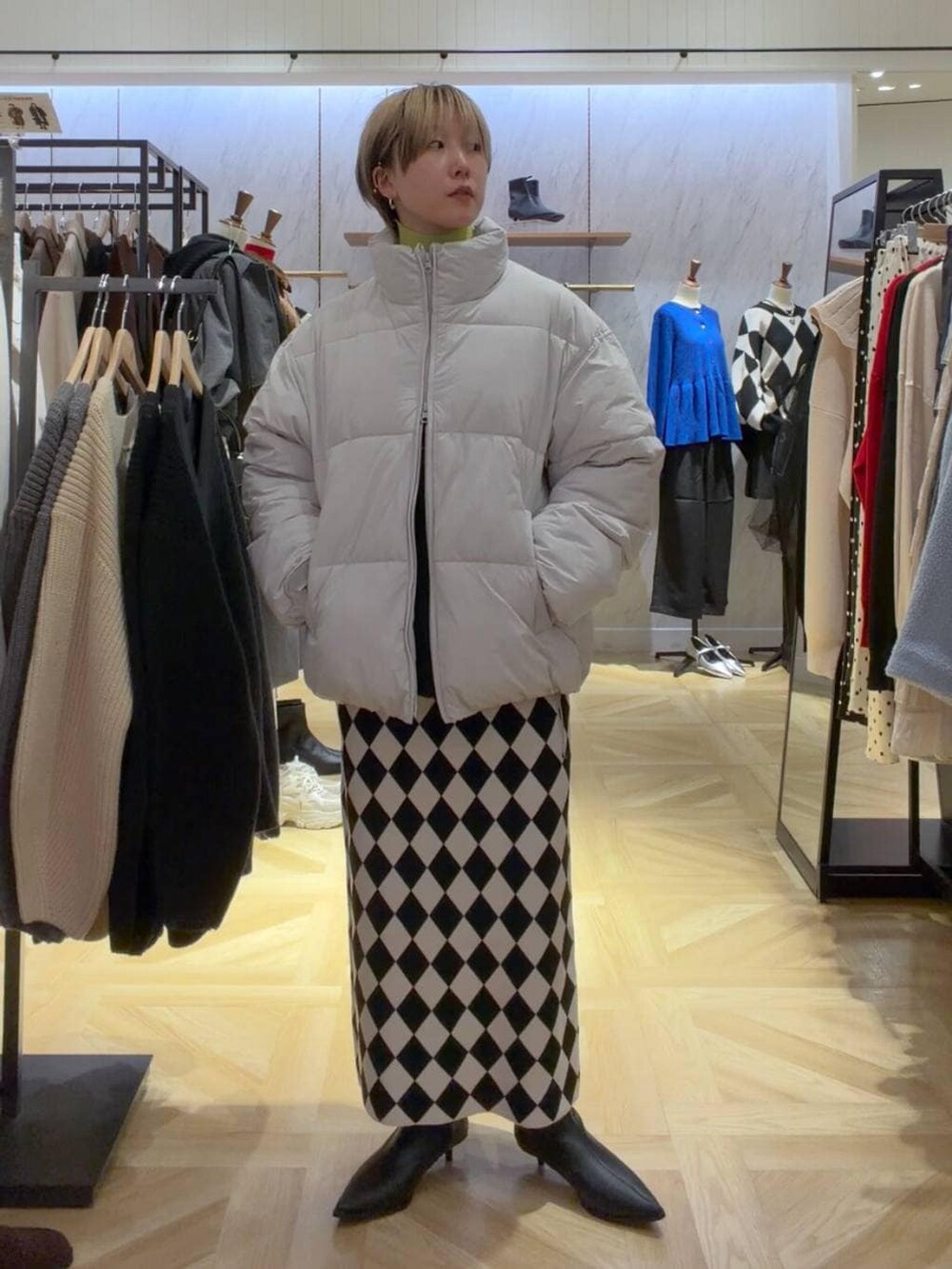 イエロー系のニット/セーター、グレー系のダウンジャケット/コート、その他のスカートを着用したレディースの秋コーディネートの5枚目の写真