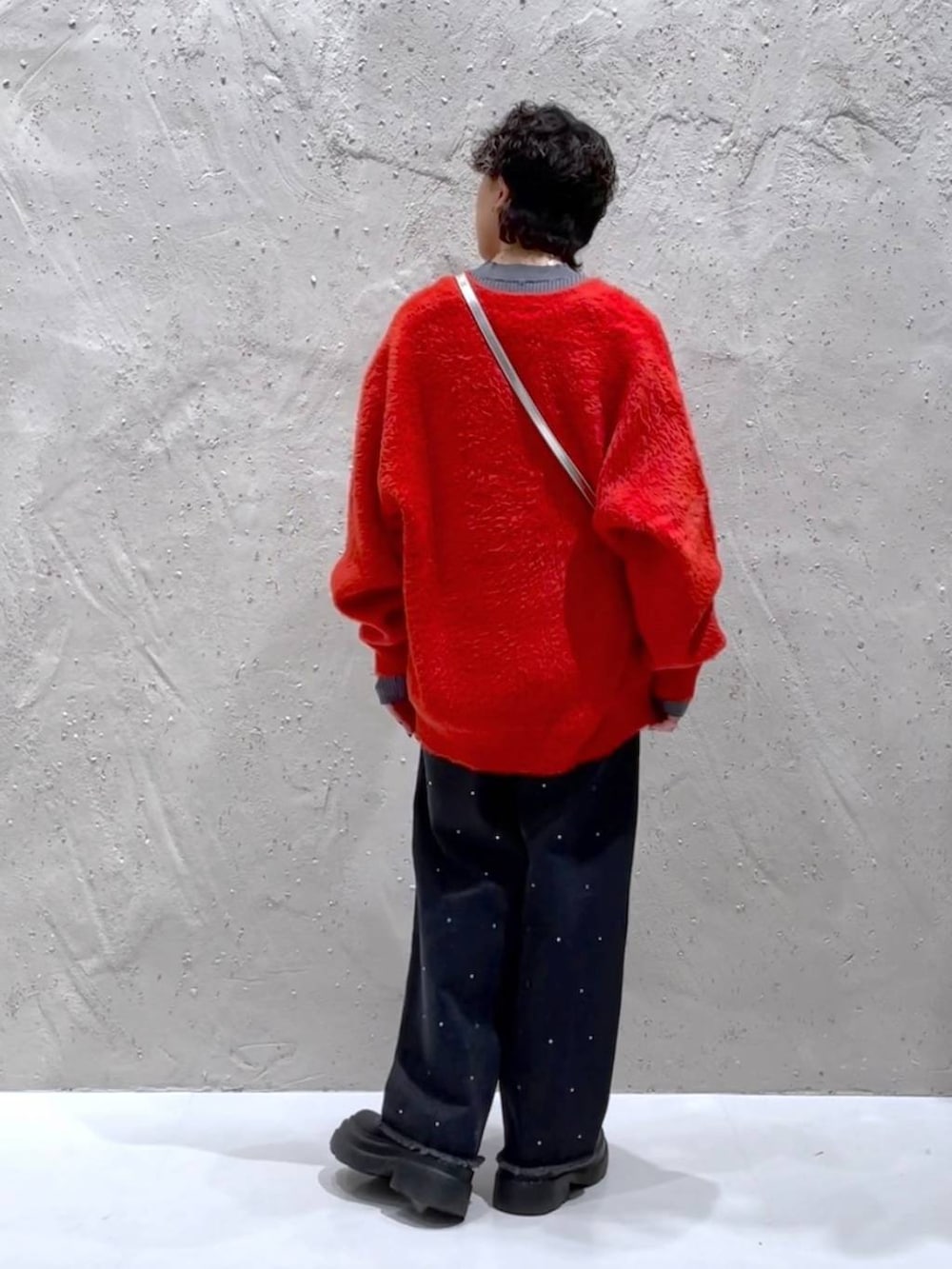 ブラック系のブーツ、シルバー系のボストンバッグ、オレンジ系のニット/セーターを着用したレディースの冬コーディネートの3枚目の写真