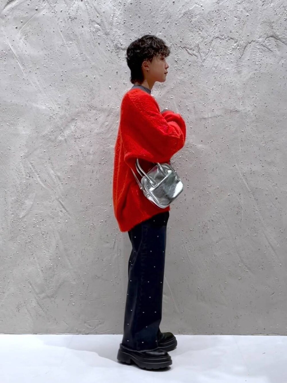 ブラック系のブーツ、シルバー系のボストンバッグ、オレンジ系のニット/セーターを着用したレディースの冬コーディネートの2枚目の写真