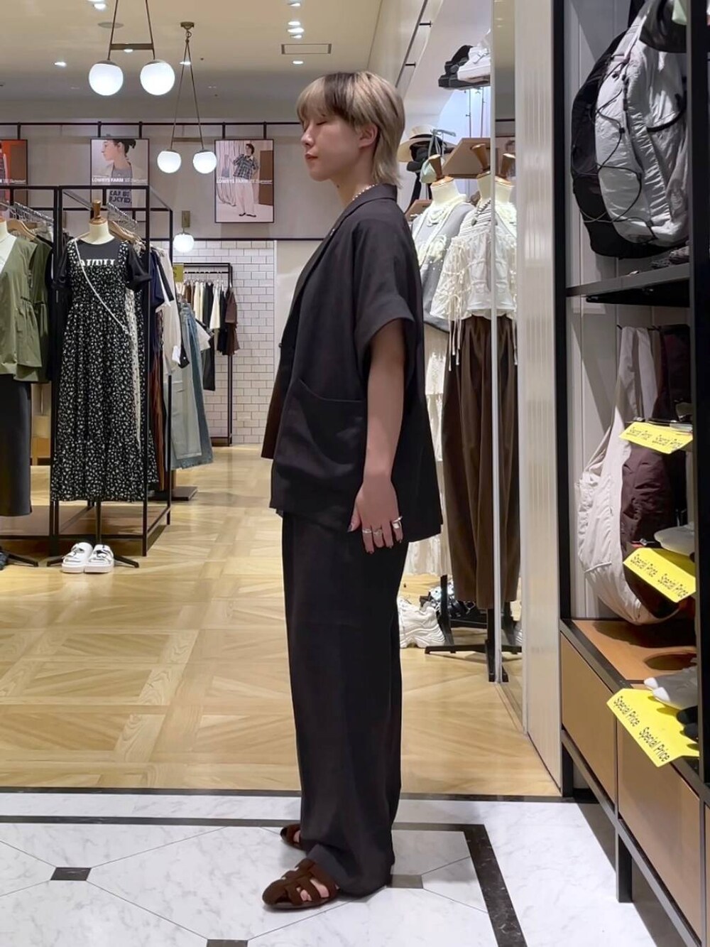 グレー系のテーラードジャケット、グレー系のスラックス、ブラウン系のサンダルを着用したレディースの夏コーディネートの2枚目の写真