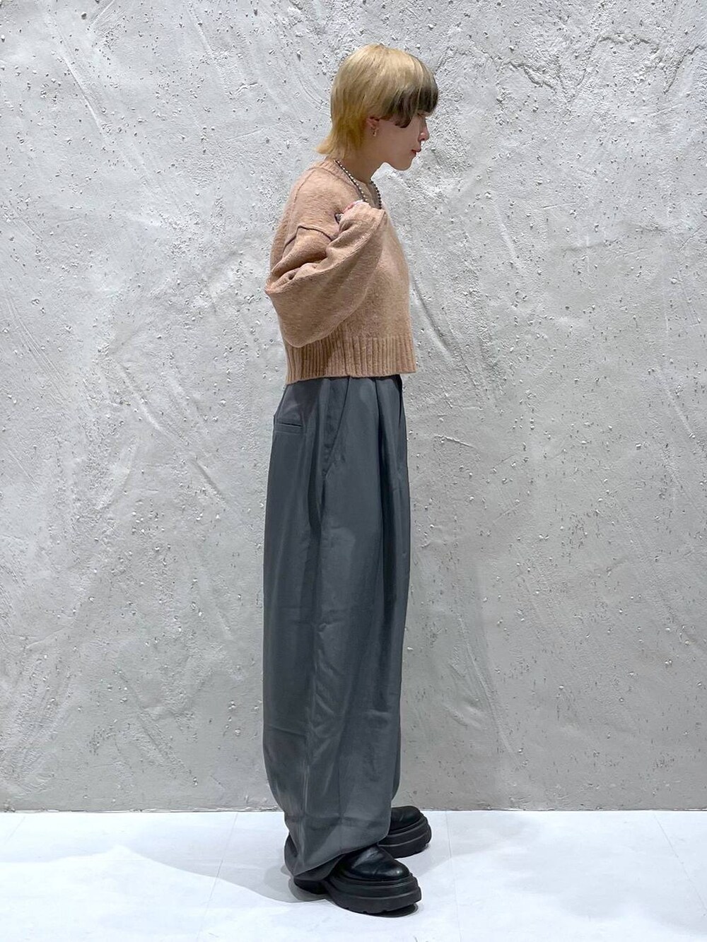 オレンジ系のニット/セーター、グレー系のその他パンツを着用したレディースの秋コーディネートの2枚目の写真