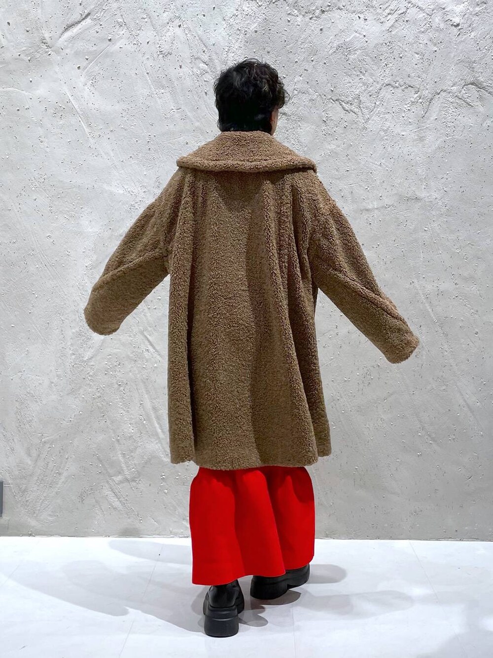 ブラック系のブーツ、ブラウン系のその他アウター、レッド系のワンピースを着用したレディースの冬コーディネートの3枚目の写真