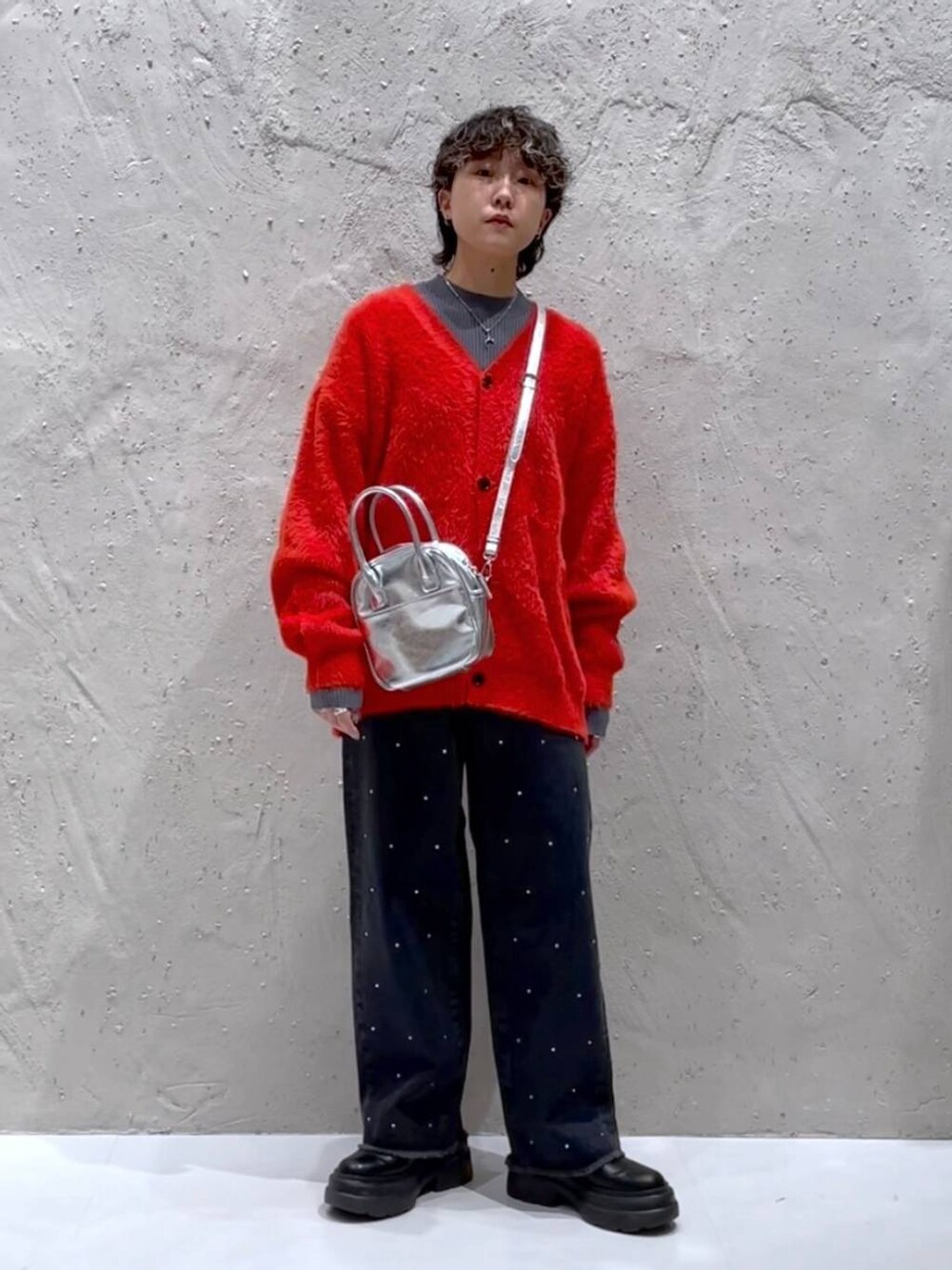 ブラック系のブーツ、シルバー系のボストンバッグ、オレンジ系のニット/セーターを着用したレディースの冬コーディネートの6枚目の写真