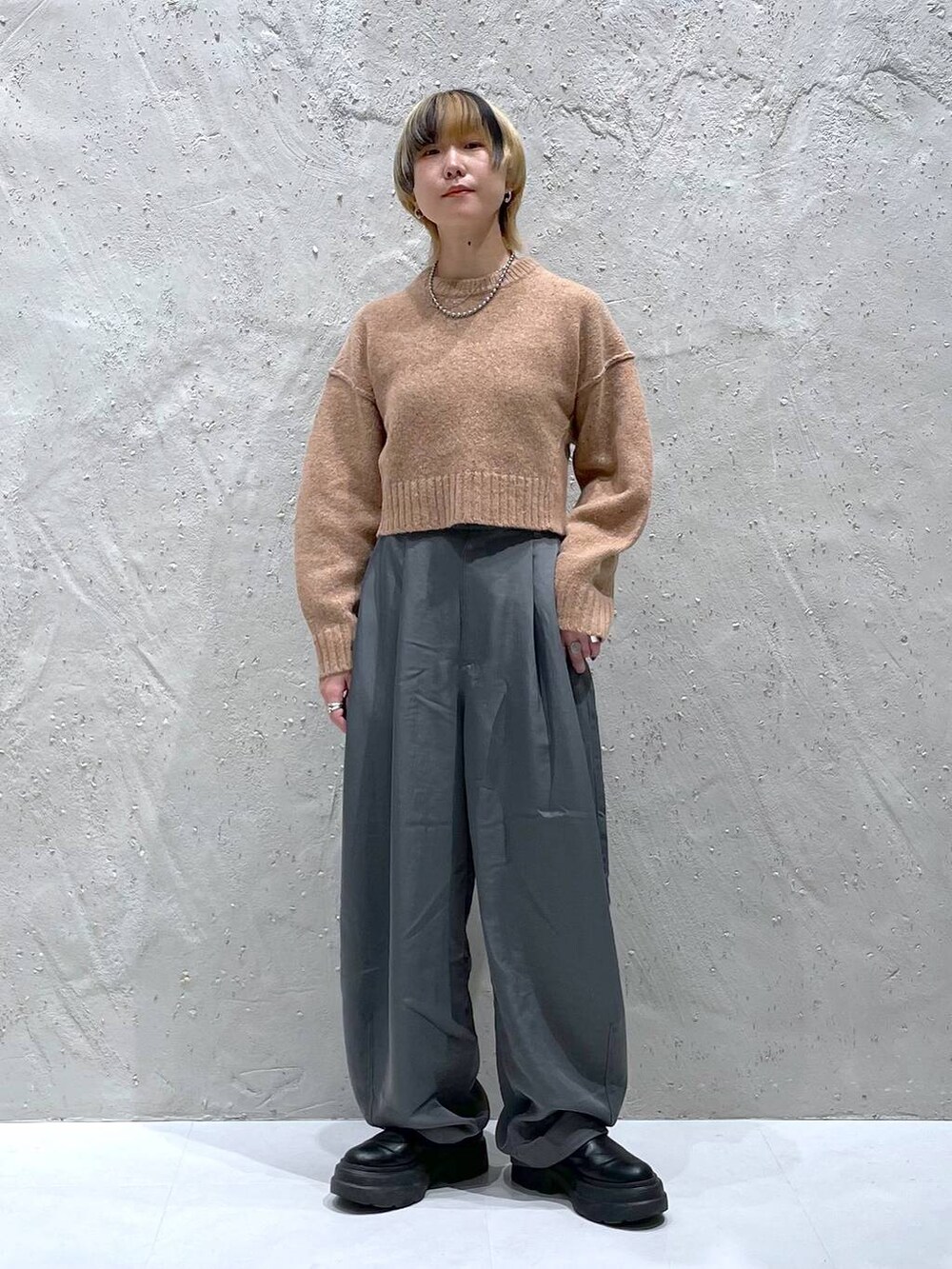 オレンジ系のニット/セーター、グレー系のその他パンツを着用したレディースの秋コーディネートの5枚目の写真