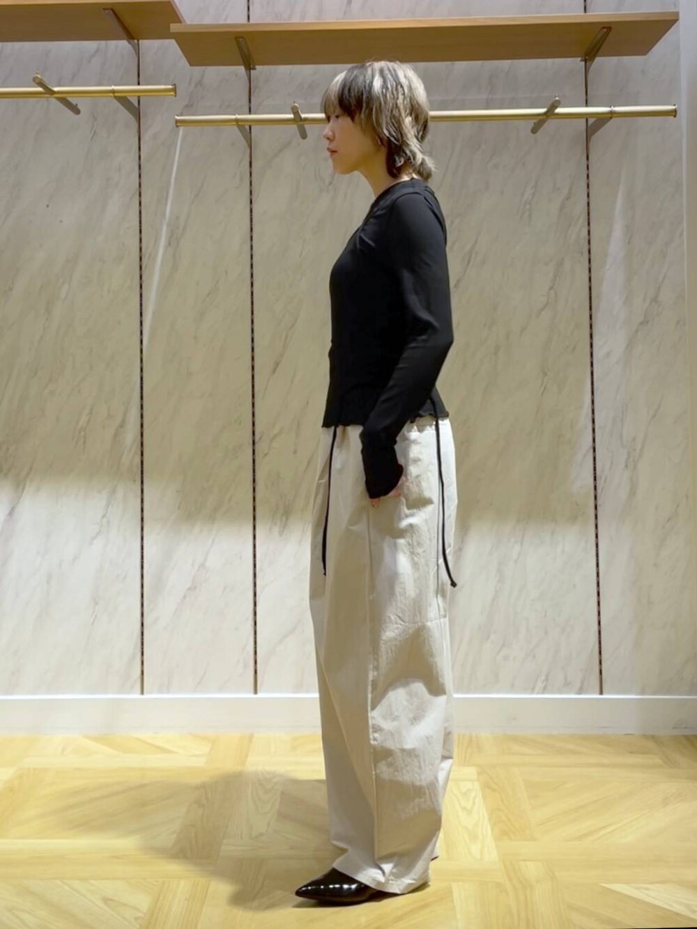 ブラック系のパンプス、ホワイト系のスラックス、ブラック系のショルダーバッグを着用したレディースの春コーディネートの4枚目の写真