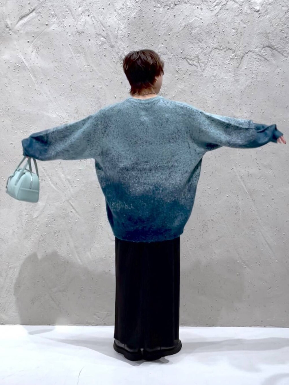 グリーン系のニット/セーター、グリーン系のボストンバッグ、ブラック系のスカートを着用したレディースの秋コーディネートの3枚目の写真