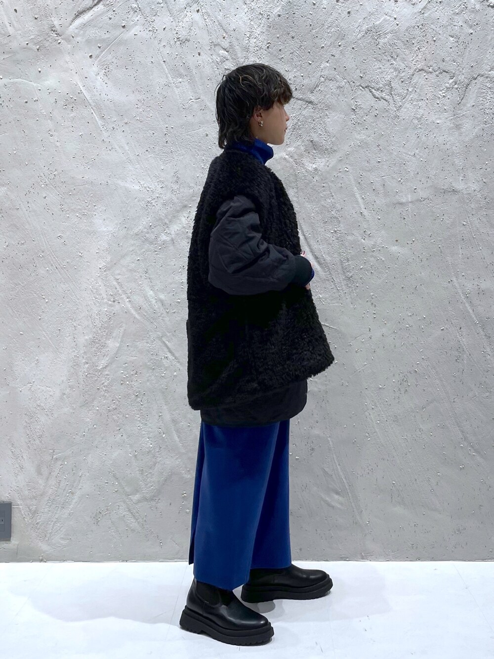 ブラック系のブルゾン、ブルー系のワンピース、ブラック系のブーツを着用したレディースの冬コーディネートの2枚目の写真