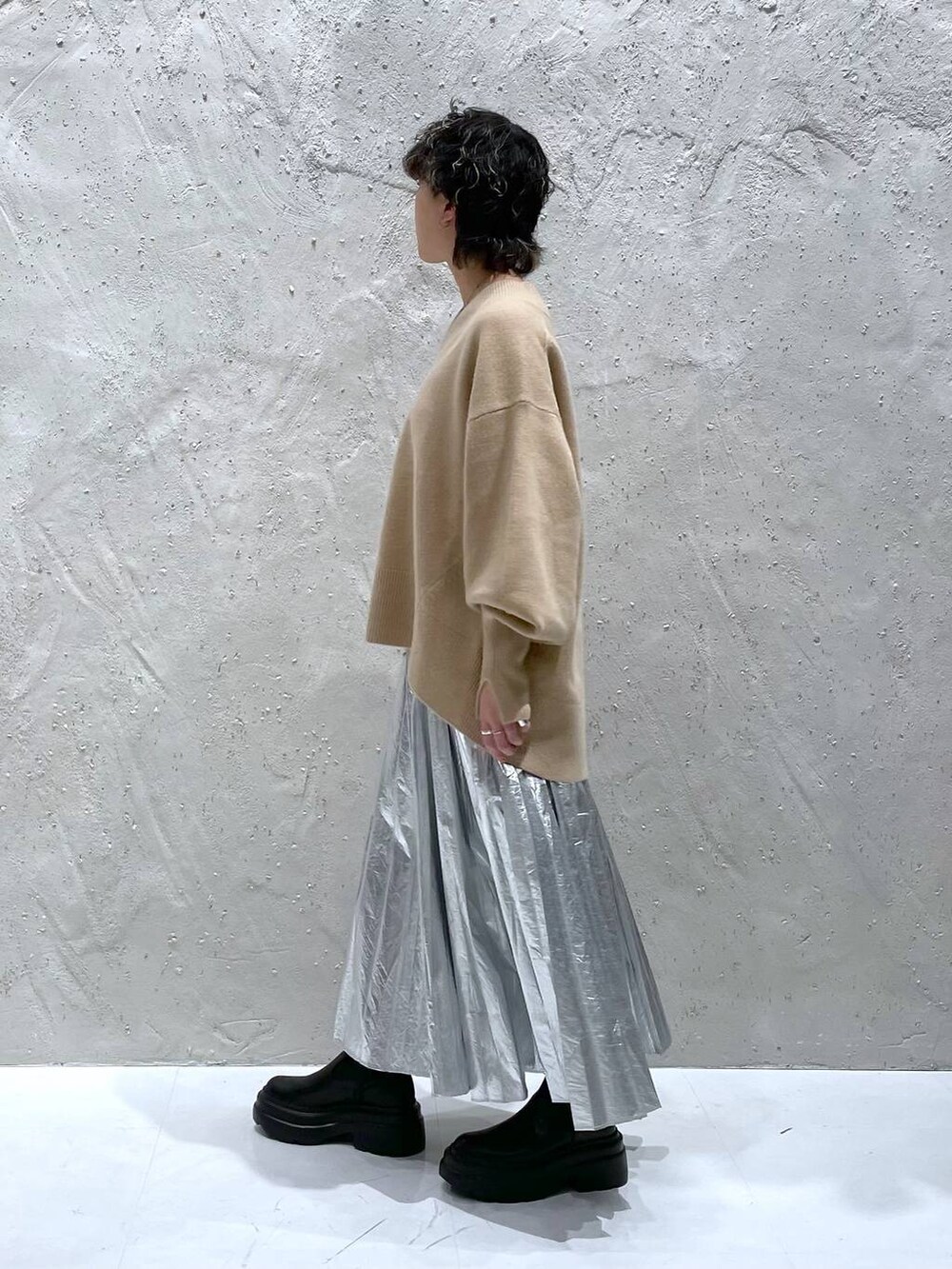 ブラック系のブーツ、ベージュ系のニット/セーター、シルバー系のスカートを着用したレディースの秋コーディネートの4枚目の写真