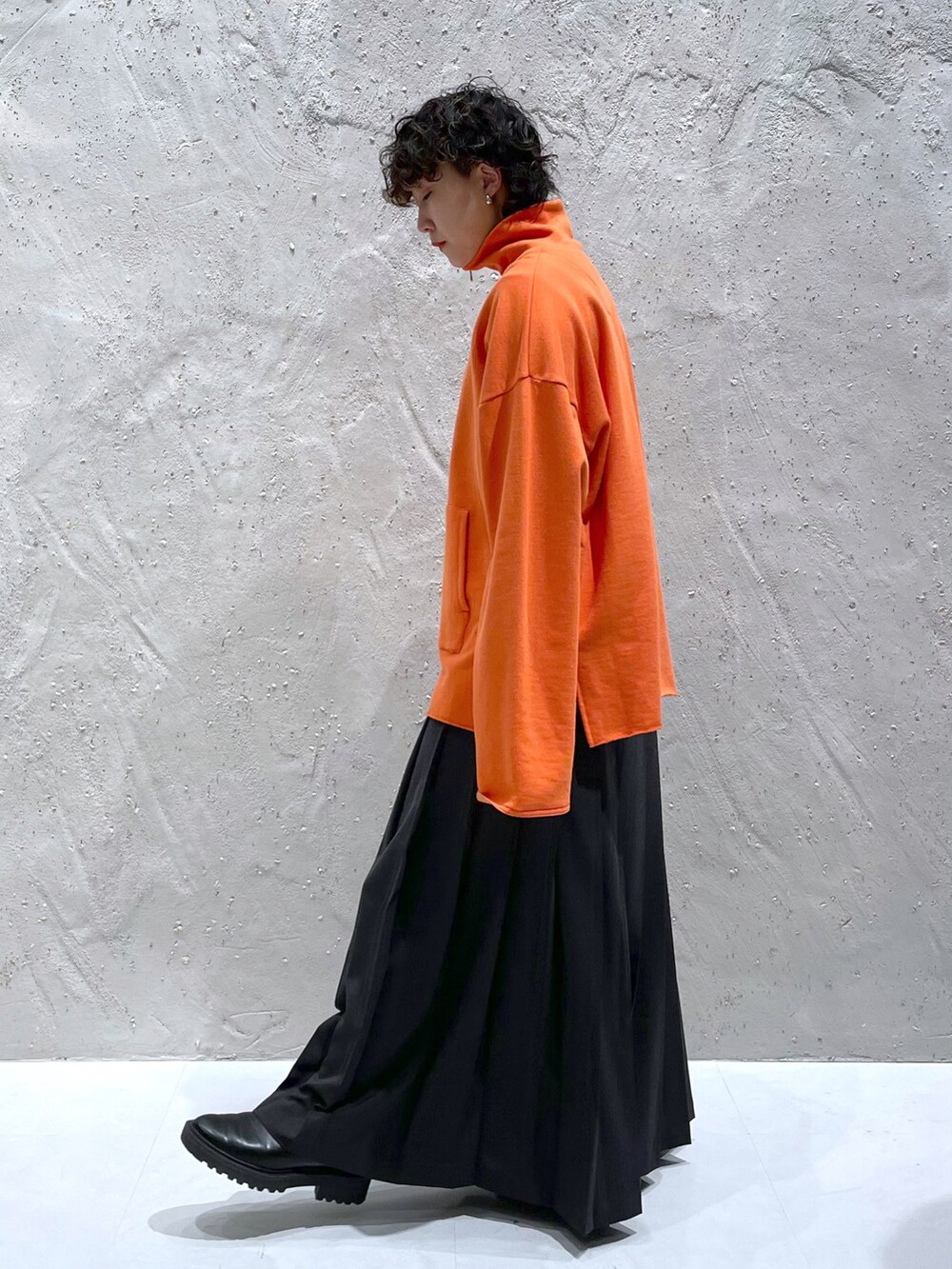 オレンジ系のスウェット、グレー系のスカート、ブラック系のブーツを着用したレディースの冬コーディネートの2枚目の写真