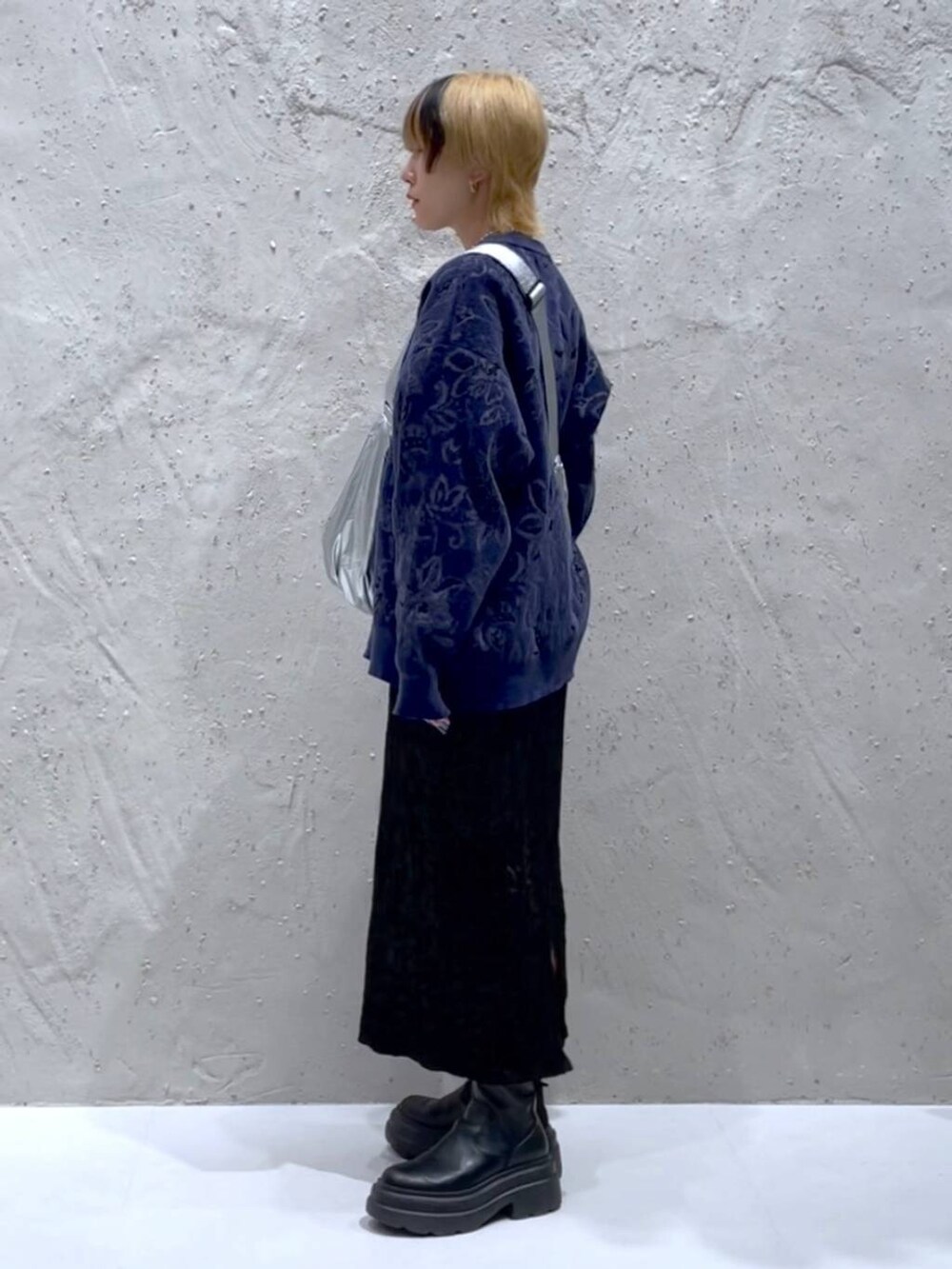 ブルー系のニット/セーター、ブラック系のスカート、シルバー系のショルダーバッグを着用したレディースの秋コーディネートの2枚目の写真