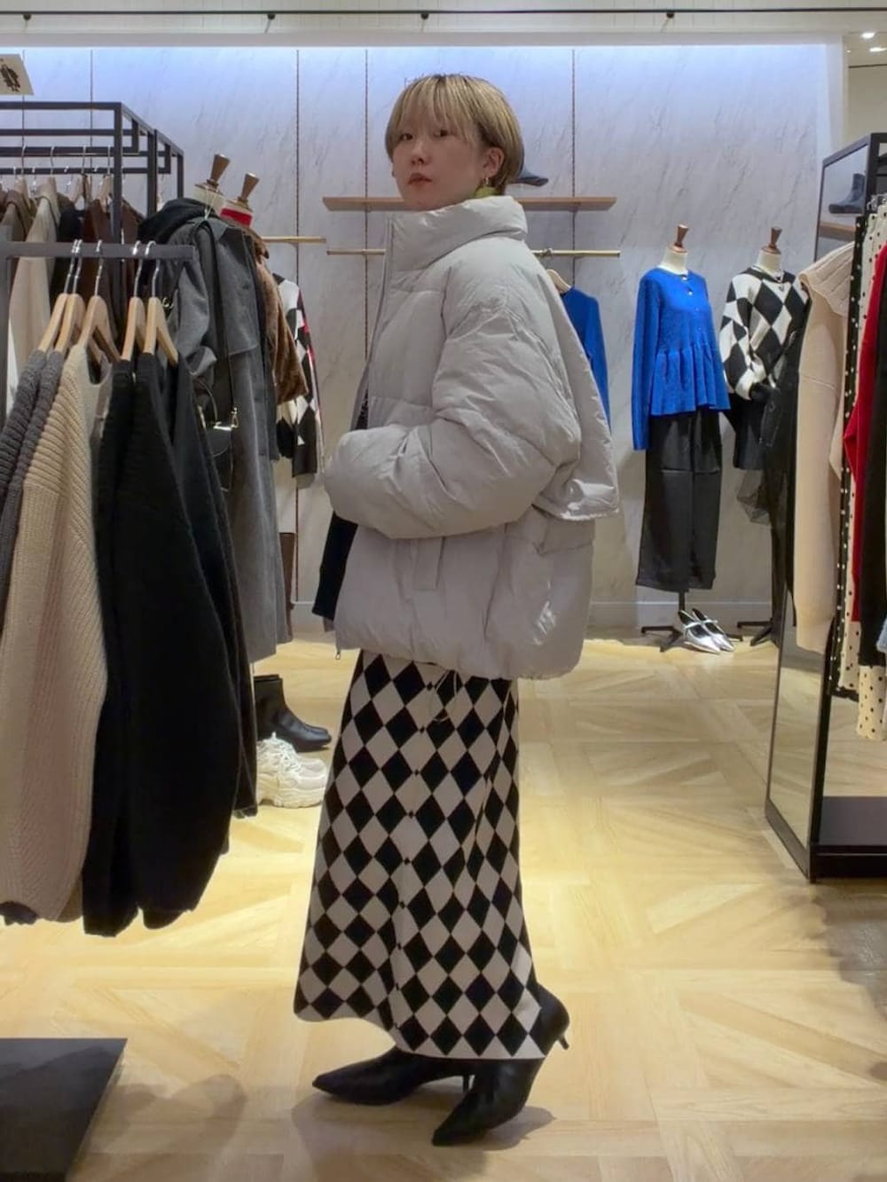 イエロー系のニット/セーター、グレー系のダウンジャケット/コート、その他のスカートを着用したレディースの秋コーディネートの4枚目の写真