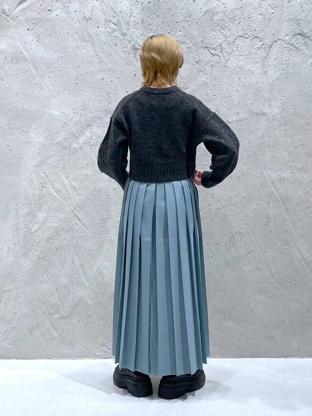 グレー系のニット/セーター、ブルー系のスカートを着用したレディースの秋コーディネートの3枚目の写真