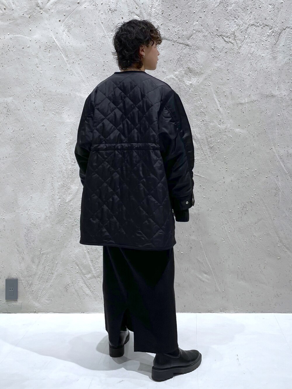 ブラック系のミリタリージャケット、ブラック系のワンピース、ブラック系のブーツを着用したレディースの冬コーディネートの4枚目の写真