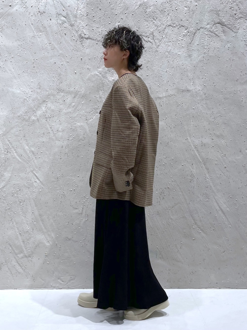 ブラック系のワンピース、ベージュ系のテーラードジャケット、ホワイト系のブーツを着用したレディースの秋コーディネートの2枚目の写真