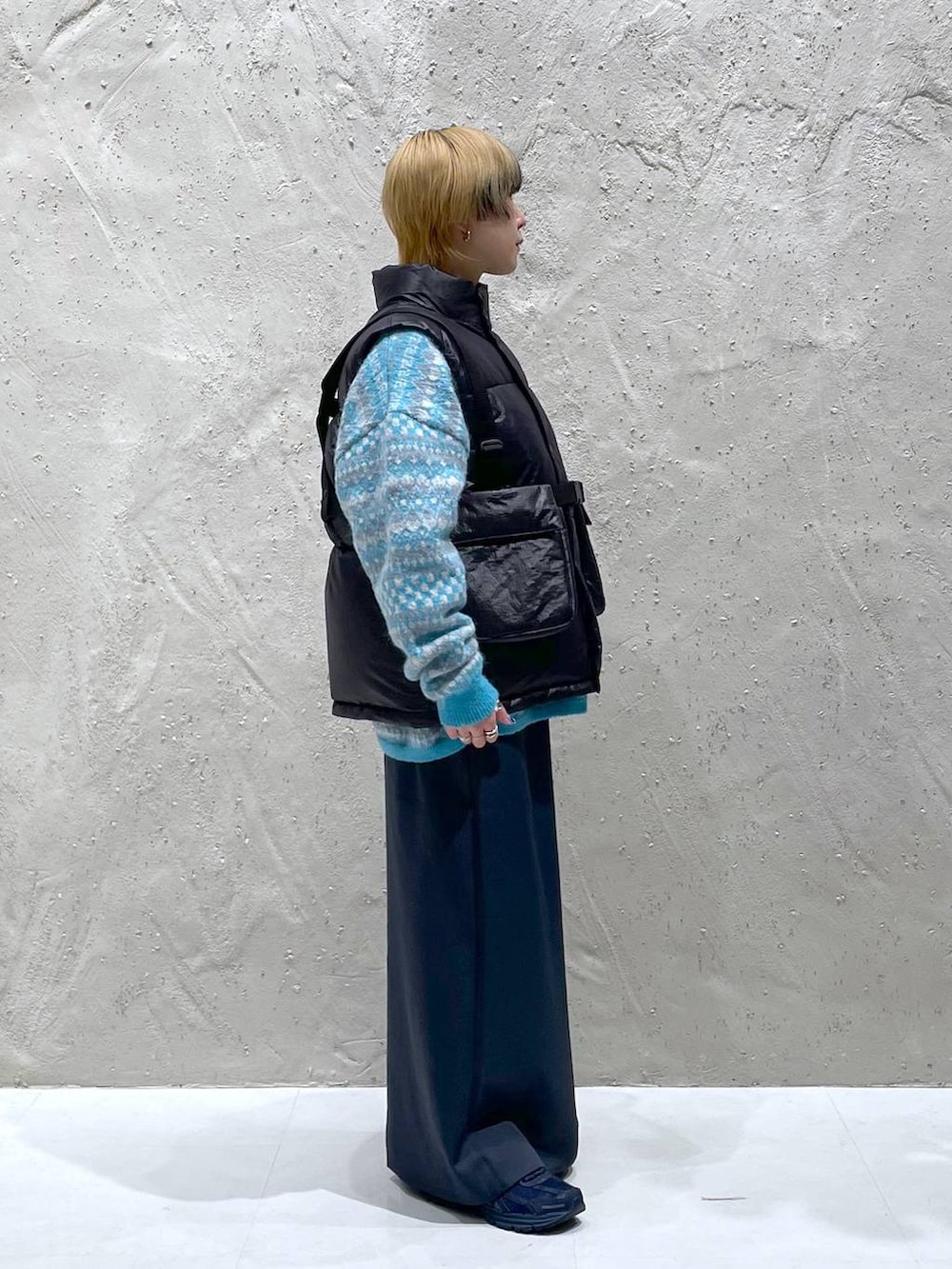 ブルー系のニット/セーター、グリーン系のスカート、ブラック系のダウンベストを着用したレディースの秋コーディネートの4枚目の写真