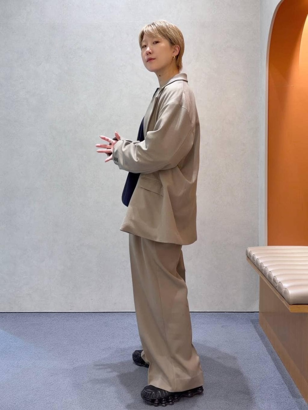 ブルー系のニット/セーター、ベージュ系のスラックス、ベージュ系のテーラードジャケットを着用したメンズの春コーディネートの2枚目の写真