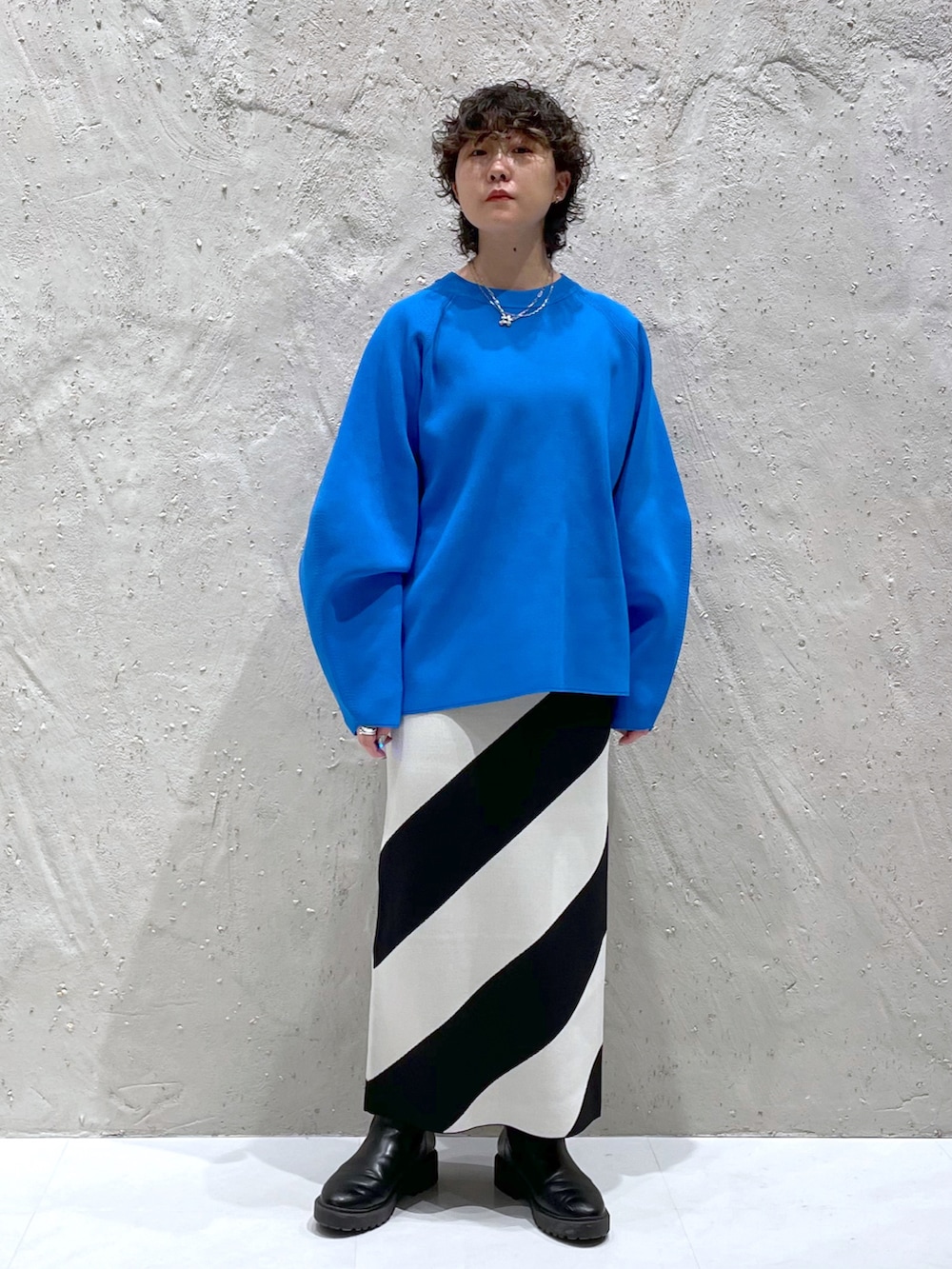 ブルー系のニット/セーター、ブラック系のスカート、ブラック系のブーツを着用したレディースの冬コーディネートの4枚目の写真