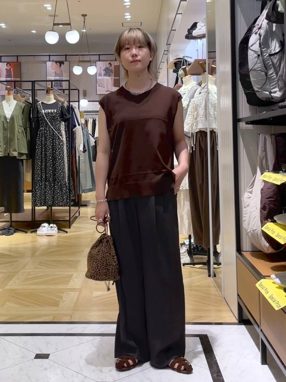 グレー系のテーラードジャケット、グレー系のスラックス、ブラウン系のサンダルを着用したレディースの夏コーディネートの6枚目の写真