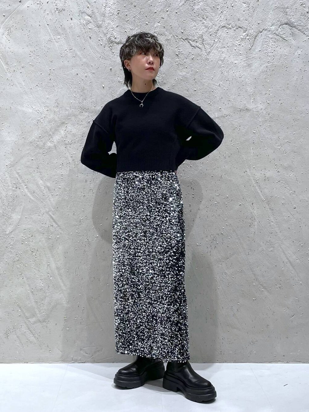 ブラック系のブーツ、ブラック系のニット/セーター、シルバー系のスカートを着用したレディースの秋コーディネートの5枚目の写真