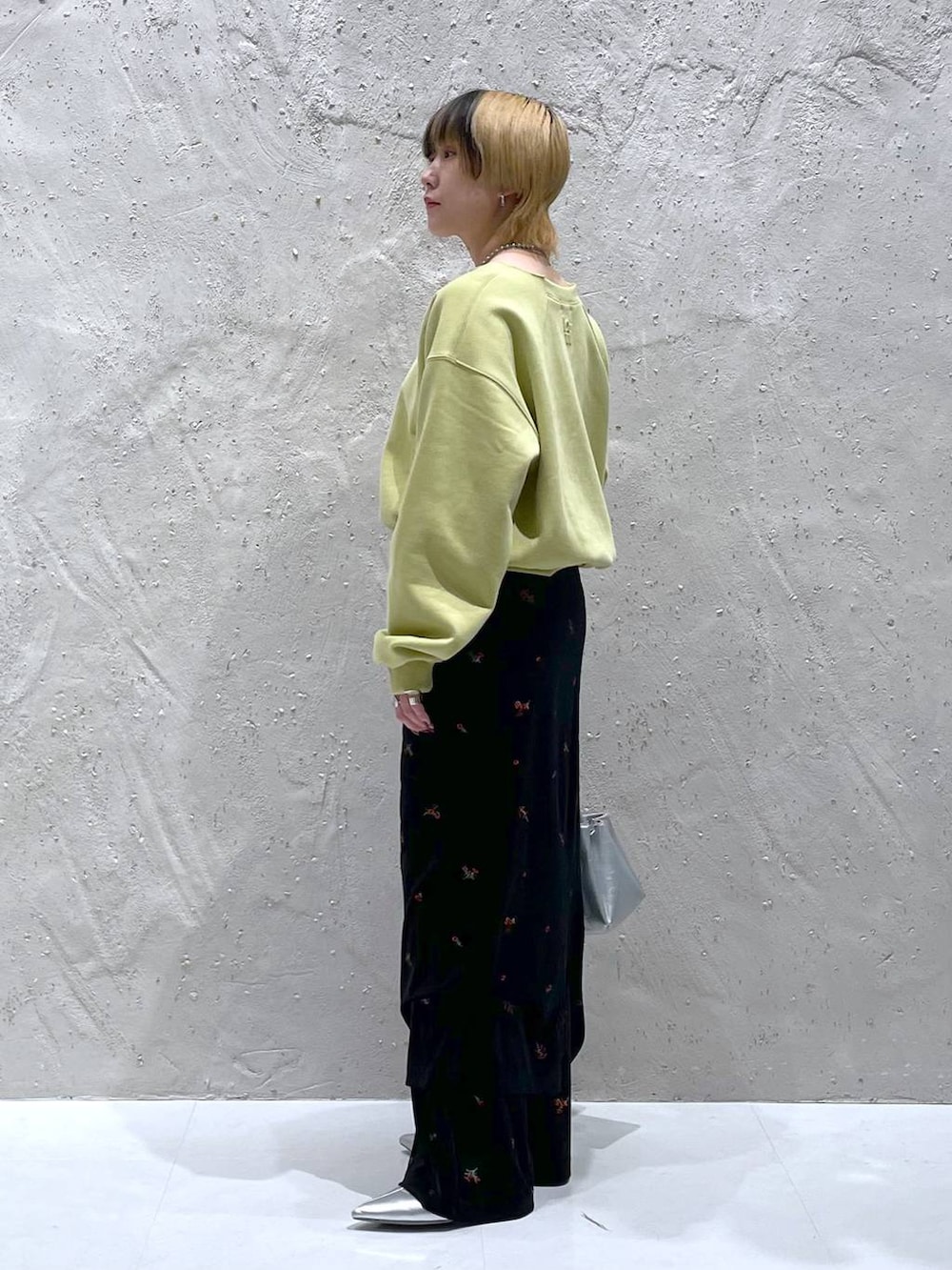 イエロー系のスウェット、シルバー系のショルダーバッグ、シルバー系のブーツを着用したレディースの秋コーディネートの2枚目の写真