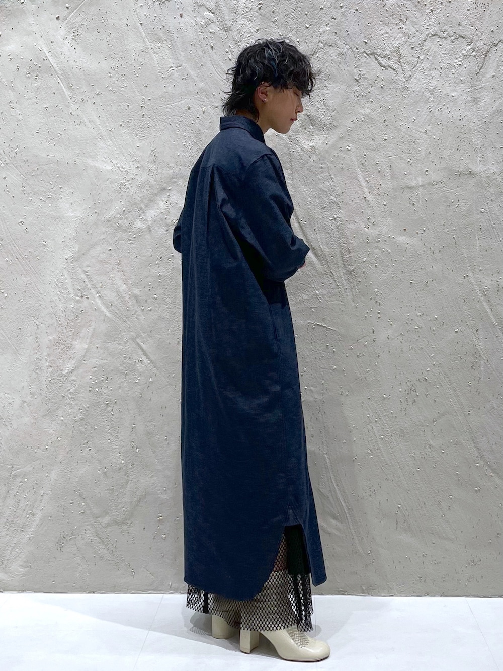 ブルー系のシャツワンピース、ブラック系のスカート、ホワイト系のブーツを着用したレディースの春コーディネートの2枚目の写真