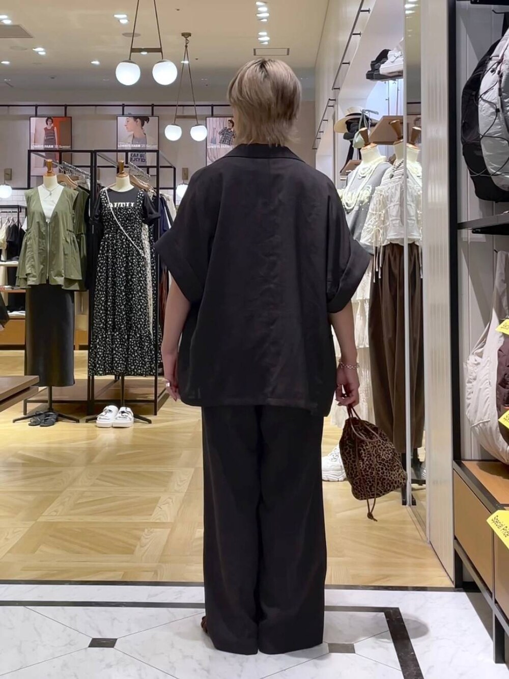 グレー系のテーラードジャケット、グレー系のスラックス、ブラウン系のサンダルを着用したレディースの夏コーディネートの3枚目の写真