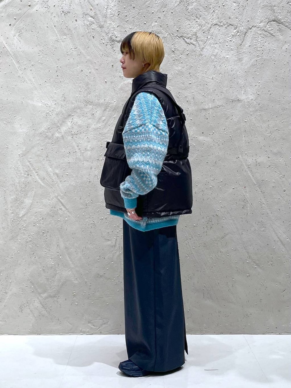 ブルー系のニット/セーター、グリーン系のスカート、ブラック系のダウンベストを着用したレディースの秋コーディネートの2枚目の写真