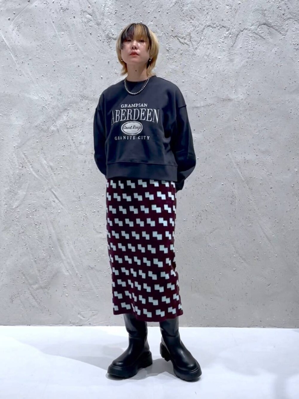 グレー系のスウェット、ブラック系のボストンバッグ、ブラウン系のスカートを着用したレディースの秋コーディネートの4枚目の写真