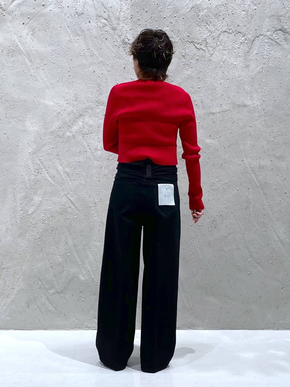 ブラック系のパンプス、レッド系のニット/セーター、ブラック系のデニムパンツを着用したレディースの秋コーディネートの3枚目の写真