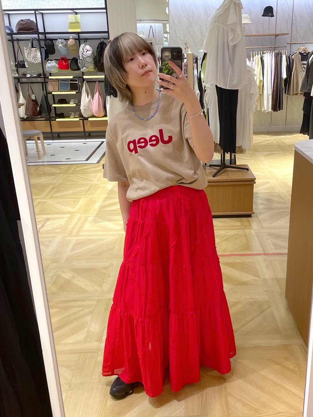 レッド系のスカート、ベージュ系のTシャツ/カットソーを着用したレディースの春コーディネートの3枚目の写真