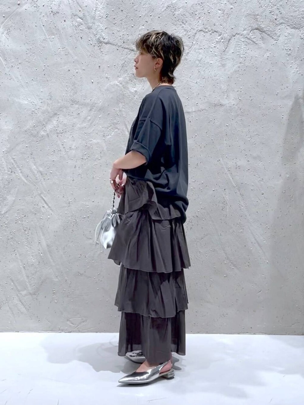 シルバー系のパンプス、シルバー系のショルダーバッグ、ブラック系のTシャツ/カットソーを着用したレディースの夏コーディネートの2枚目の写真