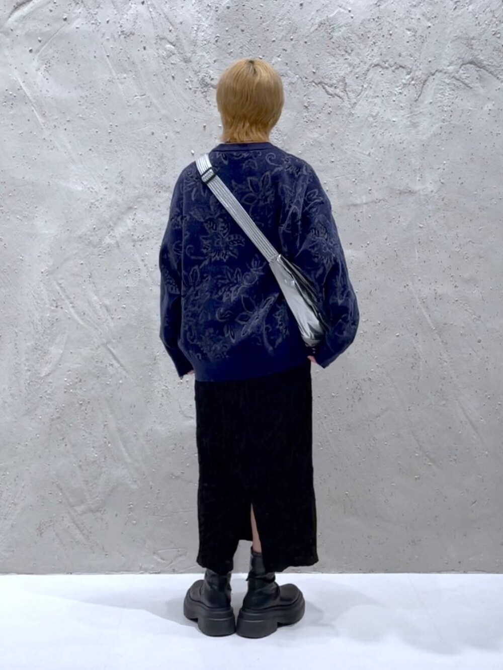 ブルー系のニット/セーター、ブラック系のスカート、シルバー系のショルダーバッグを着用したレディースの秋コーディネートの3枚目の写真