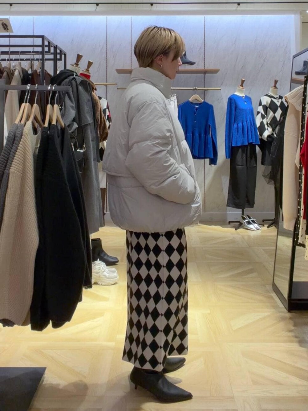 イエロー系のニット/セーター、グレー系のダウンジャケット/コート、その他のスカートを着用したレディースの秋コーディネートの2枚目の写真