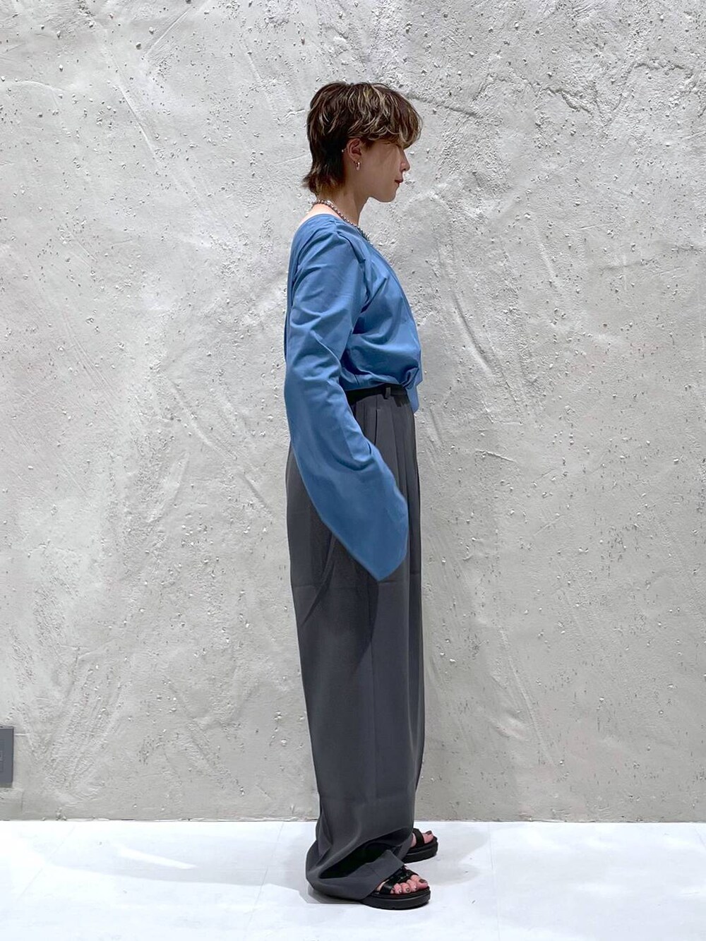 グレー系のスラックス、ブルー系のTシャツ/カットソーを着用したレディースの夏コーディネートの2枚目の写真