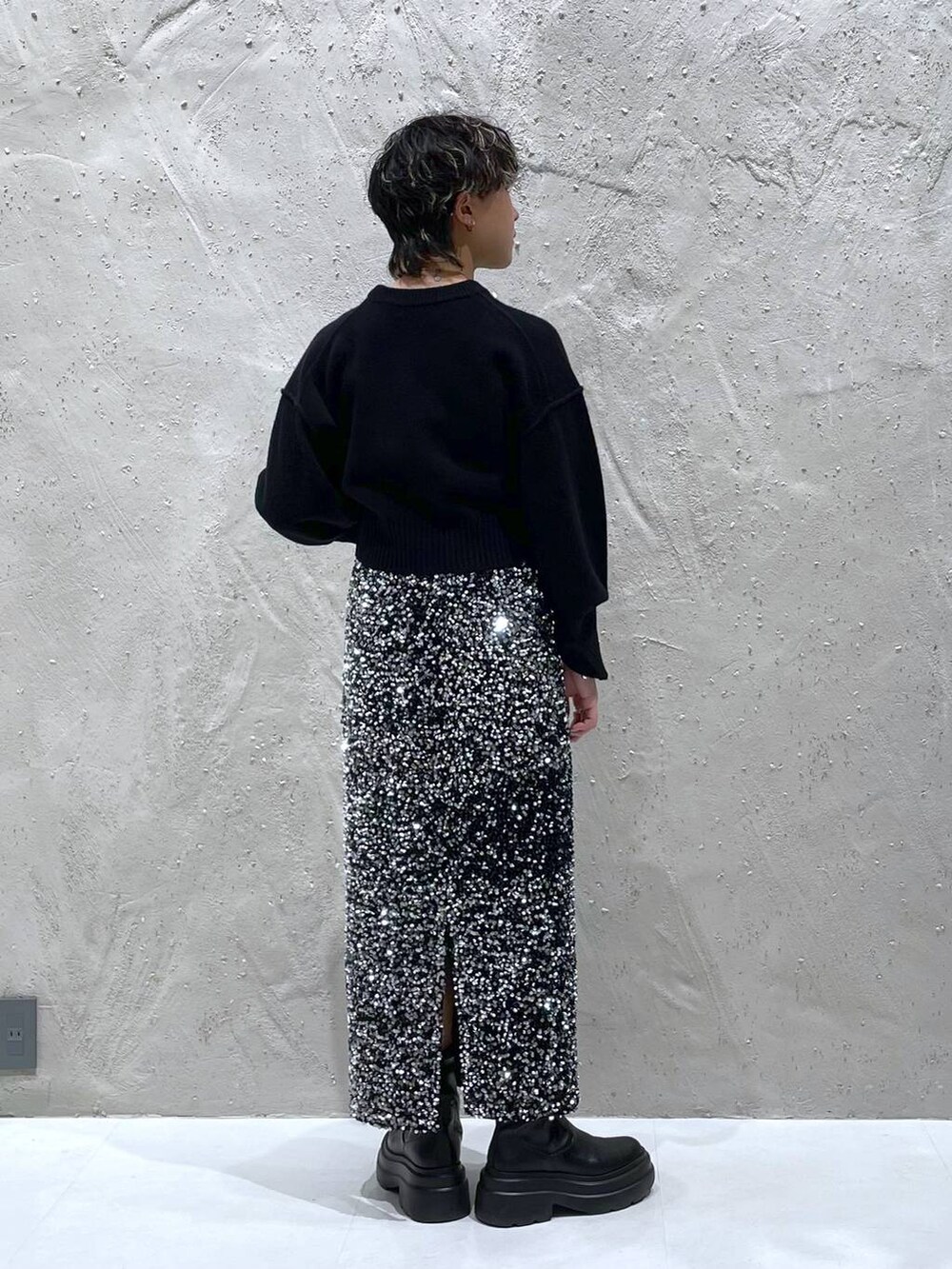 ブラック系のブーツ、ブラック系のニット/セーター、シルバー系のスカートを着用したレディースの秋コーディネートの3枚目の写真